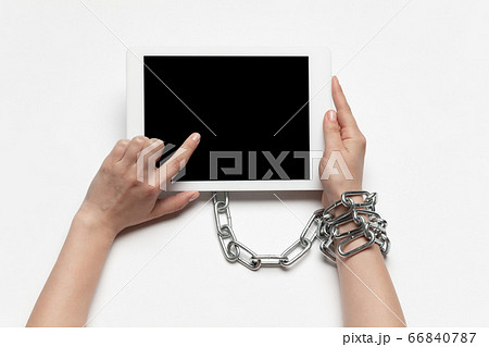 Close up of human hand using tablet with blank black screen. Tied with chain, addiction Close up of human hand using tablet with blank black screen. Tied with chain, addiction 66840787