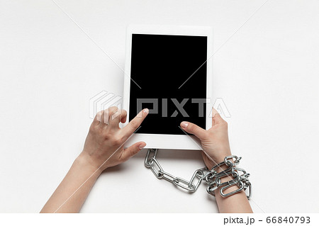 Close up of human hand using tablet with blank black screen. Tied with chain, addiction Close up of human hand using tablet with blank black screen. Tied with chain, addiction 66840793