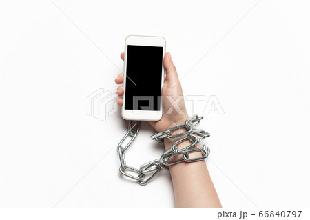 Close up of human hand using smartphone with blank black screen. Tied with chain, addiction 66840797