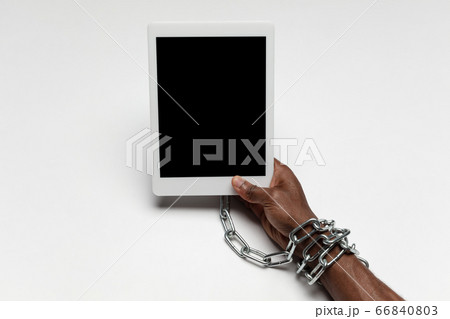 Close up of human hand using tablet with blank black screen. Tied with chain, addiction Close up of human hand using tablet with blank black screen. Tied with chain, addiction 66840803