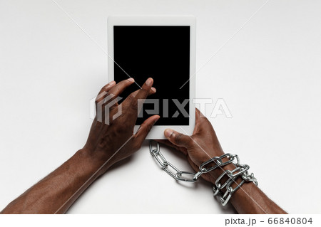 Close up of human hand using tablet with blank black screen. Tied with chain, addiction Close up of human hand using tablet with blank black screen. Tied with chain, addiction 66840804