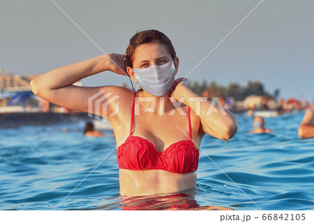 One young woman in a surgical mask bathes in sea. 66842105