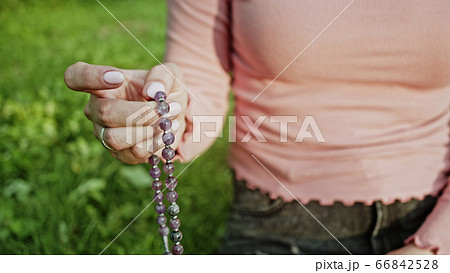 Woman lit hand close up counts rosary - malas strands of gemstones beads used for keeping count Woman lit hand close up counts rosary - malas strands of gemstones beads used for keeping count 66842528