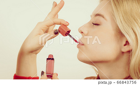 Woman applying lipstick or lip gloss Woman applying lipstick or lip gloss 66843756