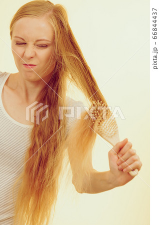 Blonde girl brushing her long hair 66844437