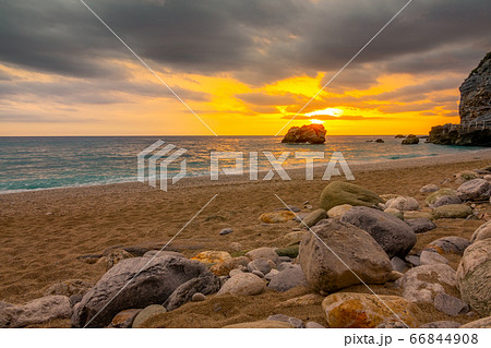 Sunset Over the Sea and Stones on a Sandy Beach Sunset Over the Sea and Stones on a Sandy Beach 66844908