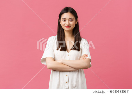 Beauty, people emotions and summer lifestyle concept. Tender young asian girl in cute dress smiling camera, standing with crossed hands and professional determined look, pink background 66848867