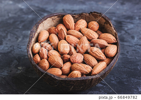 Almonds in coconut shells on a dark background Almonds in coconut shells on a dark background 66849782