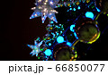 Close up of large yellow balls on blurry luminous multi-pointed blue stars background and decoration on Christmas tree square at Christmas market square 66850077