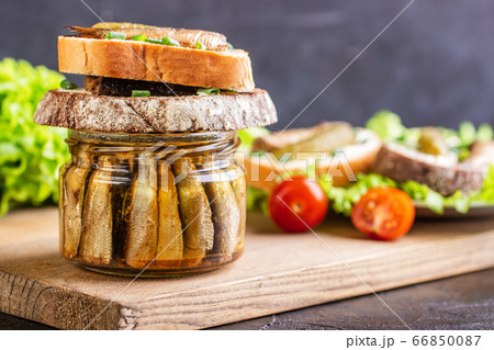 Two sandwiches lie on a jar with fish and a wooden 66850087