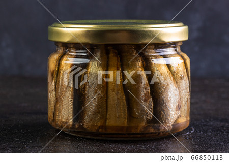 Glass jar of sprats against a dark background Glass jar of sprats against a dark background 66850113
