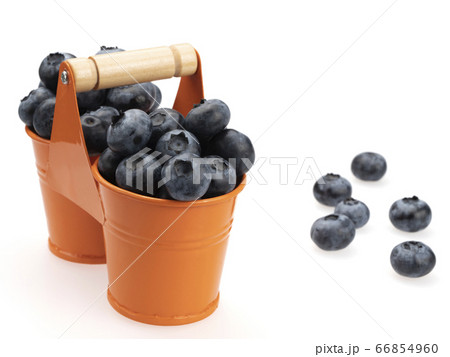 Berries of ripe blueberries in two orange buckets, and scattered around them, on a white background. Berries of ripe blueberries in two orange buckets, and scattered around them, on a white background. 66854960