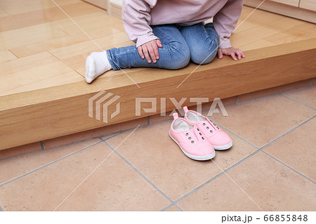 玄関で靴を揃える4歳の女の子の写真素材