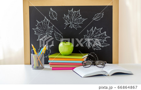 books, apple and school supplies on table at home 66864867