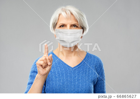 senior woman in medical mask pointing finger up 66865627