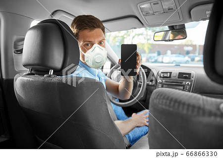 male car driver in mask showing smartphone 66866330