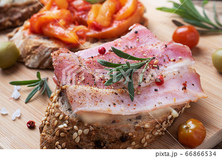 Wholegrain bread sandwiches with cream cheese, bacon and olives canned peppers with tomato on wooden background. 66866534