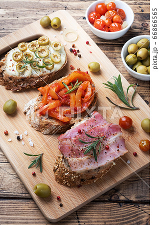 Wholegrain bread sandwiches with cream cheese, bacon and olives canned peppers with tomato on wooden background. Wholegrain bread sandwiches with cream cheese, bacon and olives canned peppers with tomato on wooden background. 66866565
