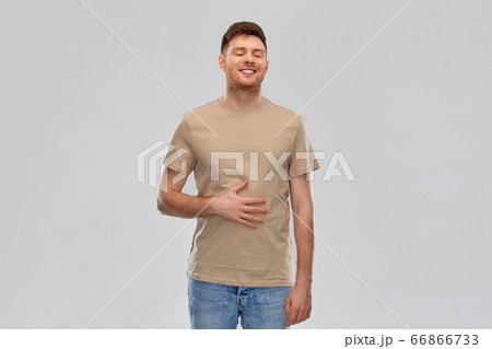 happy full man touching tummy over gray background 66866733