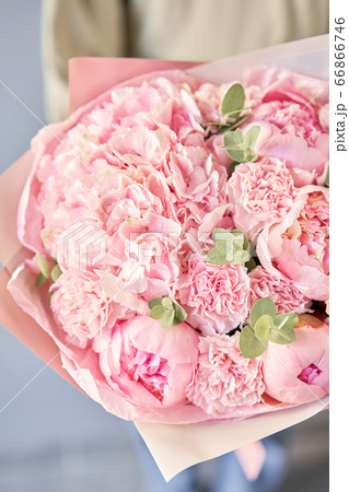 Bouquet of pink peonies and carnations in womans hands. Modern floral shop. Finished work of the florist. Delivery fresh cut flower from online store 66866746