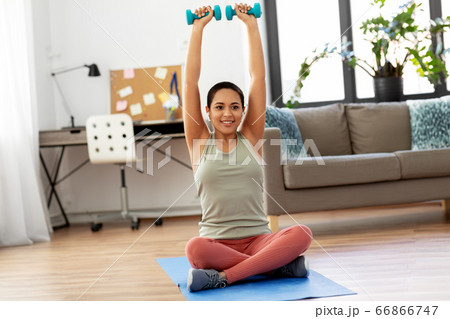 african woman with dumbbells exercising at home 66866747