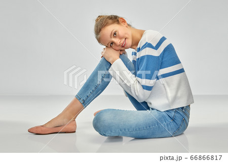 smiling teenage girl in pullover sitting on floor 66866817