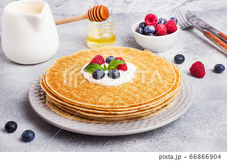 Plate of delicious thin pancakes with berries on grey table Copy space. Plate of delicious thin pancakes with berries on grey table Copy space. 66866904