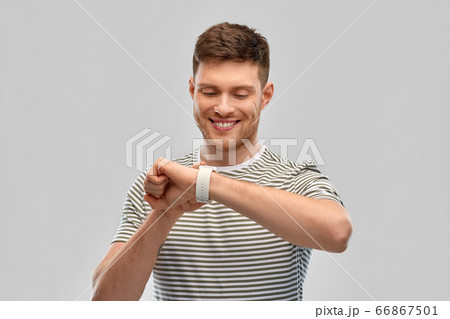 smiling young man looking at smart watch smiling young man looking at smart watch 66867501