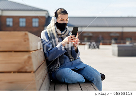 woman in face mask with smartphone in city 66868118