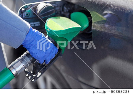 close up of hand in glove filling car with petrol 66868283