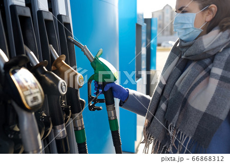 young woman wearing medical mask at gas station 66868312