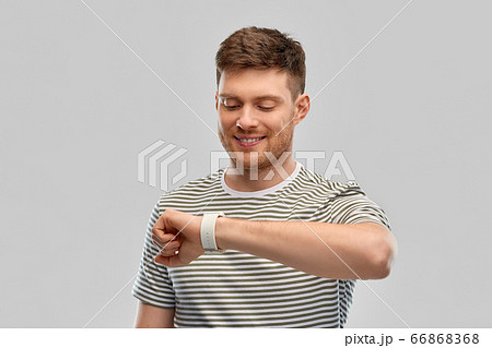smiling young man looking at smart watch 66868368