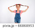 Cute small girl smailing and pulling her hair in the air, isolated on white background 66868953