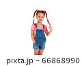 Cute small girl smailing and pulling her hair in the air, isolated on white background 66868990