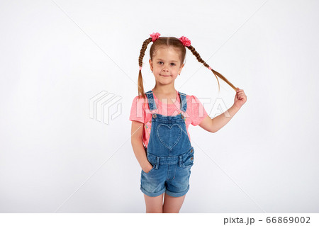 Cute small girl smailing and pulling her hair in the air, isolated on white background 66869002