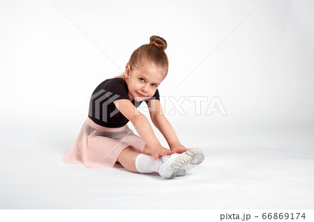 Little girl doing stretching and gymnastic exercises on a white background. Little girl doing stretching and gymnastic exercises on a white background. 66869174