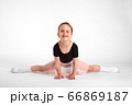 Little girl doing stretching and gymnastic exercises on a white background. 66869187