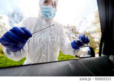 healthcare worker making coronavirus test at car 66869352