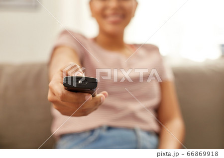 happy african american woman watching tv at home 66869918