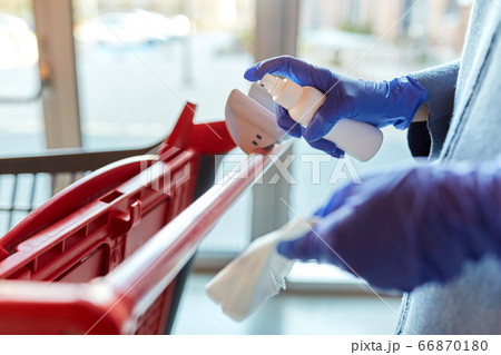 woman cleaning shopping cart handle with sanitizer 66870180