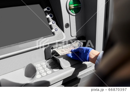 hand in medical glove with money at atm machine 66870397