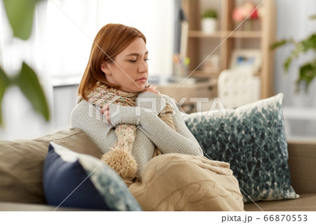 sad sick woman in blanket and scarf at home 66870553