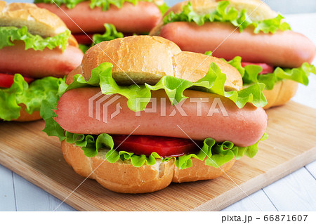 a few hot dogs on a wooden Board. Hot dog with lettuce tomato and sausage. Copy space. a few hot dogs on a wooden Board. Hot dog with lettuce tomato and sausage. Copy space. 66871607