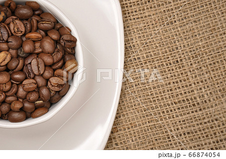 Coffee beans in a white cup on sack cloth 66874054
