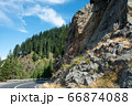 Serpentine road in the mountains. Summer sunny landscape with tall pines and rocks 66874088