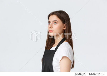 Employees, job employment, small business and coffee shop concept. Dreamy cute barista in black apron, cafe worker looking left with thoughtful smiling expression 66879405