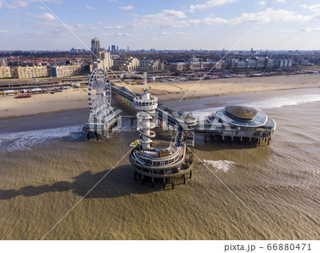 Pier with Ferris Wheel at Northern Sea Scheveningen Beach , located near the Hague city aerial drone footage. Popular Dutch beach resort Scheveningen With a clouds on the Sky in a day 66880471