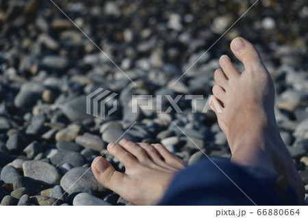 A pair of crossed legs stretched out on a sea beach. 66880664
