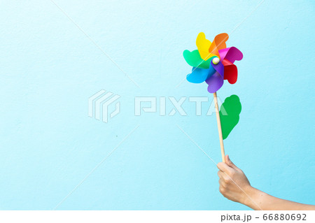 People hold colorful toy plastic turbine windmill on blue background 66880692