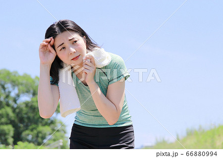 汗をぬぐい、息切れをする運動中の女性 66880994
